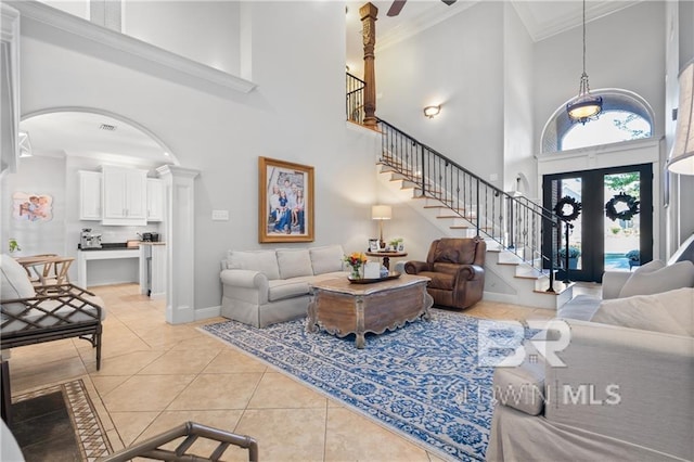 tiled living room featuring ornate columns, french doors, ornamental molding, ceiling fan, and a high ceiling