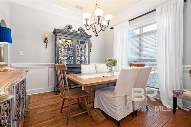 dining area with dark hardwood / wood-style floors, a notable chandelier, and ornamental molding