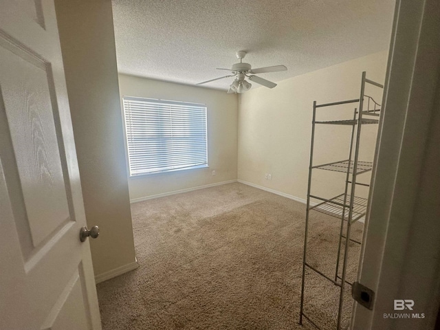 spare room featuring ceiling fan, a textured ceiling, baseboards, and carpet flooring