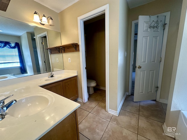 bathroom featuring double vanity, tile patterned flooring, a sink, and toilet