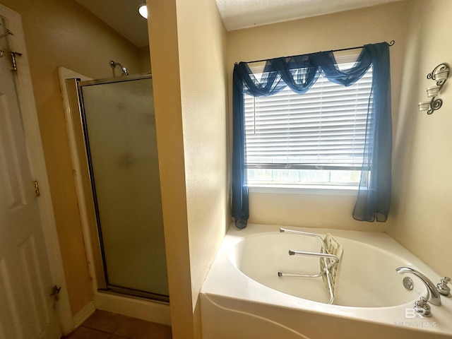 bathroom featuring a stall shower, tile patterned flooring, and a bath