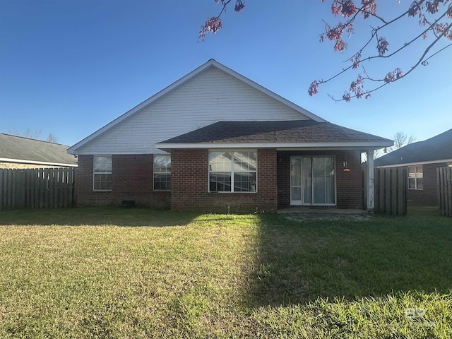 back of house with a yard, brick siding, a shingled roof, and fence