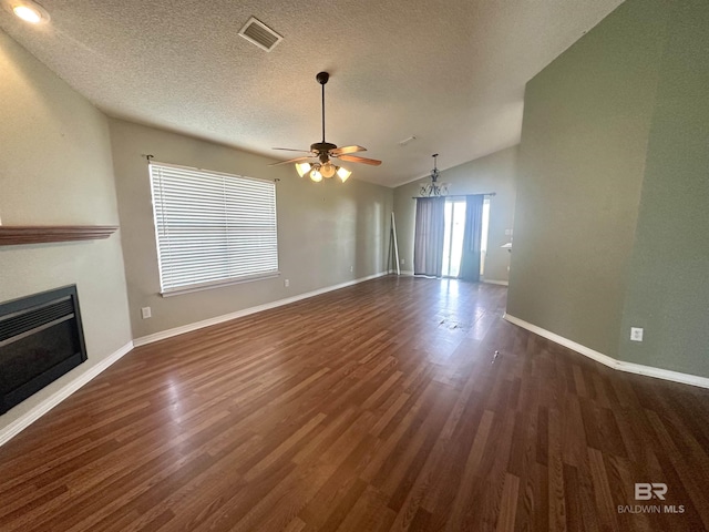 unfurnished living room with ceiling fan, lofted ceiling, visible vents, dark wood finished floors, and a glass covered fireplace