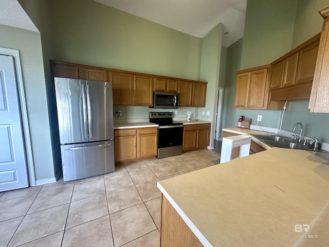 kitchen with light tile patterned floors, high vaulted ceiling, stainless steel appliances, a sink, and light countertops