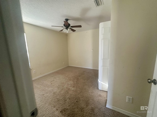 carpeted spare room featuring visible vents, ceiling fan, a textured ceiling, and baseboards