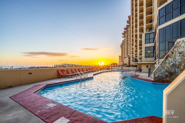 pool at dusk featuring a patio area