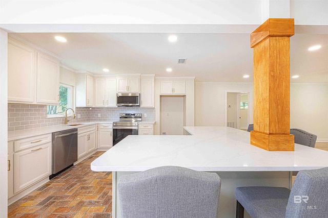 362 Azalea St, Fairhope, AL 36532 - kitchen featuring stainless steel appliances, a sink, tasteful backsplash, a breakfast bar, and white cabinets