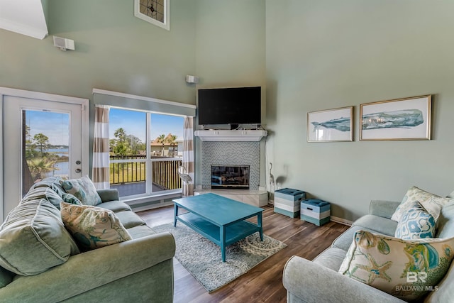 living room featuring hardwood / wood-style flooring, a towering ceiling, a fireplace, and ornamental molding