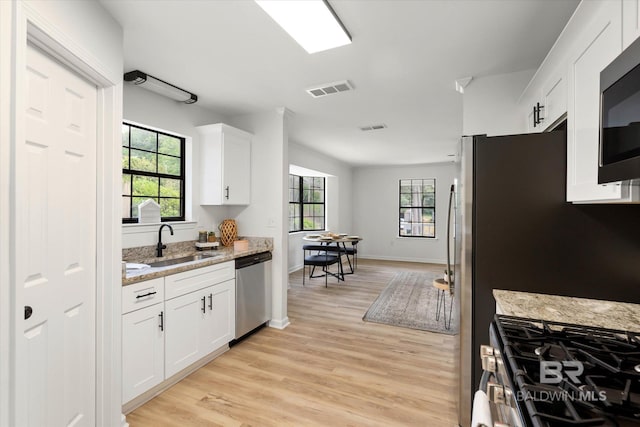 kitchen with visible vents, light wood-type flooring, white cabinets, a sink, and appliances with stainless steel finishes