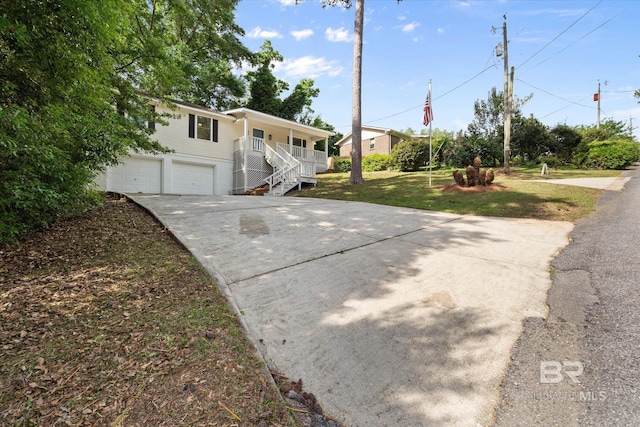 view of front of property with covered porch, driveway, stairway, a front lawn, and an attached garage