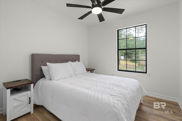 bedroom featuring baseboards, ceiling fan, and wood finished floors