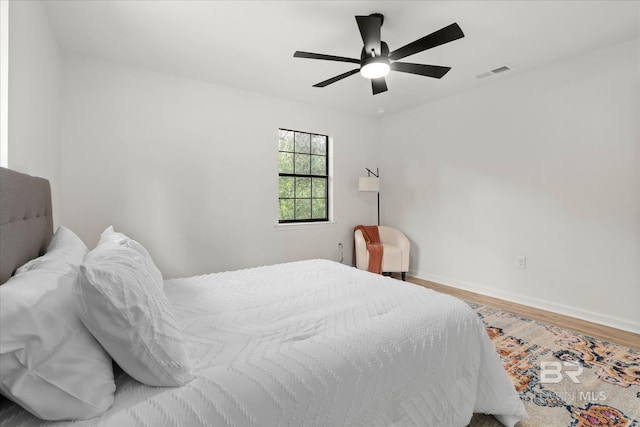 bedroom with ceiling fan, baseboards, visible vents, and wood finished floors