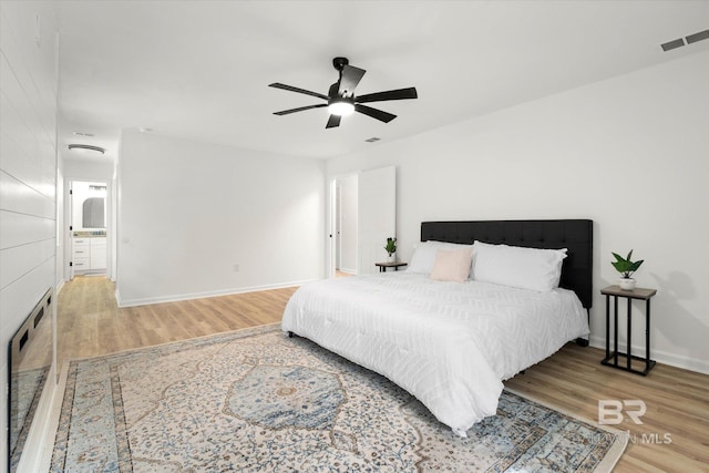 bedroom featuring visible vents, a ceiling fan, baseboards, and wood finished floors