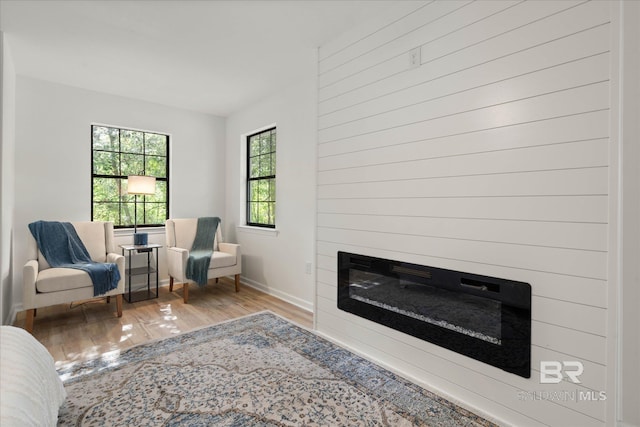 living area with baseboards, a glass covered fireplace, and wood finished floors