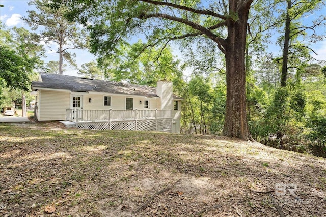 back of house with a wooden deck and a chimney