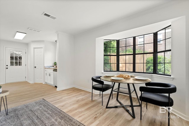 dining area featuring light wood-style floors, baseboards, visible vents, and a healthy amount of sunlight