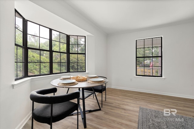 dining space featuring crown molding, baseboards, and light wood-style flooring