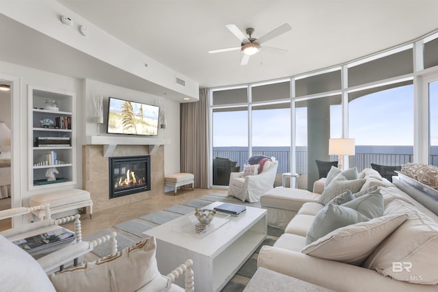 living room with tile patterned flooring, ceiling fan, built in features, and a high end fireplace