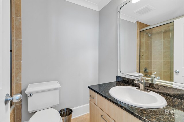 bathroom with vanity, toilet, crown molding, and a shower with door