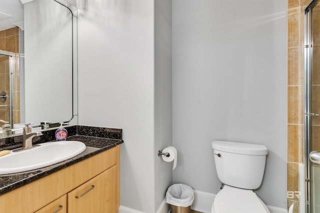 bathroom featuring toilet, an enclosed shower, and vanity