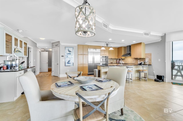 dining space with sink, crown molding, light tile patterned flooring, and a chandelier