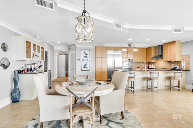 tiled dining area featuring ornamental molding, sink, and an inviting chandelier