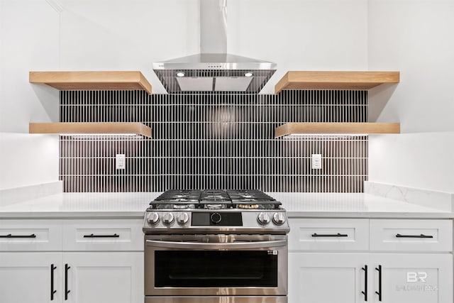 kitchen featuring stainless steel gas stove, wall chimney range hood, white cabinets, and tasteful backsplash