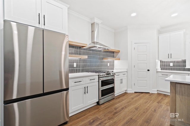 kitchen featuring white cabinetry, stainless steel appliances, and wall chimney exhaust hood