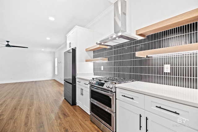 kitchen featuring appliances with stainless steel finishes, white cabinetry, tasteful backsplash, light hardwood / wood-style floors, and range hood