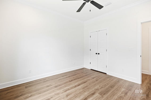 unfurnished bedroom featuring ceiling fan, a closet, ornamental molding, and light wood-type flooring