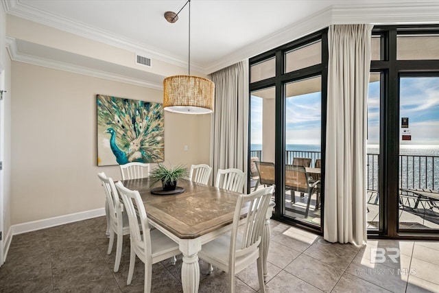 dining space with a healthy amount of sunlight, a water view, and crown molding