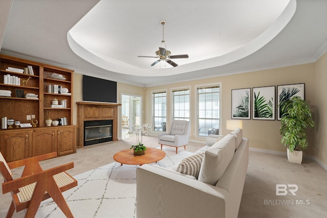 living room featuring ceiling fan, a raised ceiling, crown molding, and light carpet