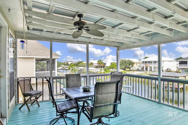 sunroom with a residential view, ceiling fan, and a water view