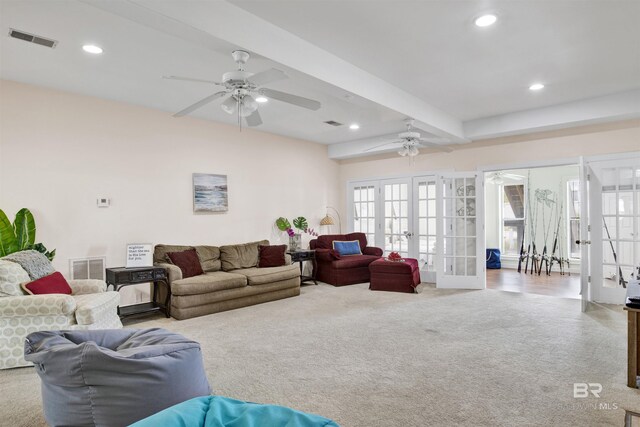 carpeted living room with beam ceiling, french doors, and ceiling fan