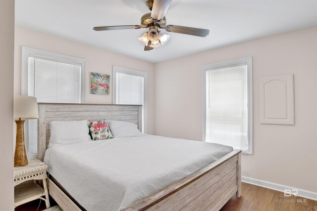 bedroom featuring multiple windows, ceiling fan, and hardwood / wood-style floors