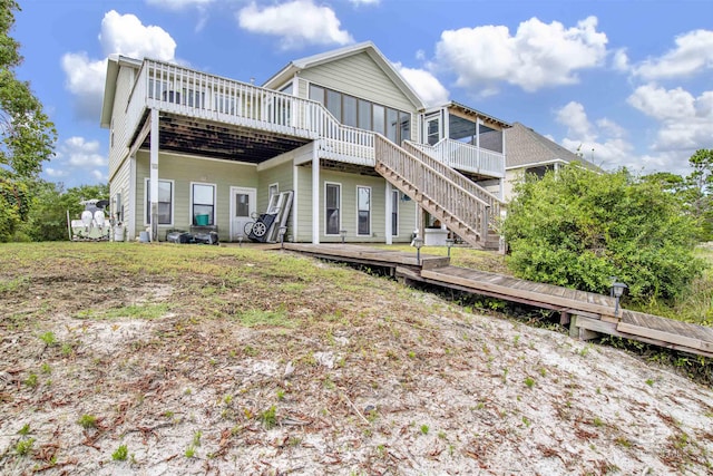 back of property with stairway, a wooden deck, and a sunroom