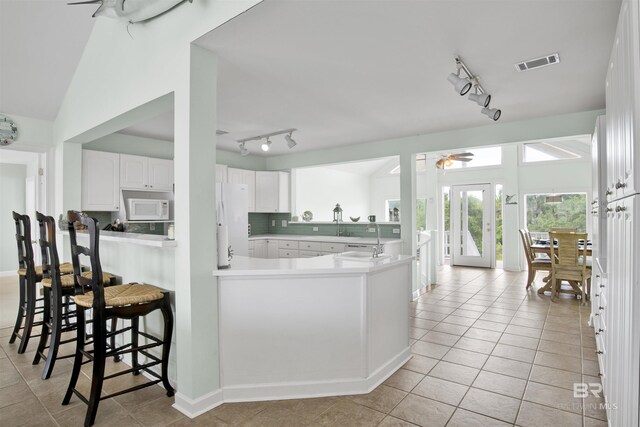 kitchen with white appliances, rail lighting, kitchen peninsula, white cabinets, and ceiling fan