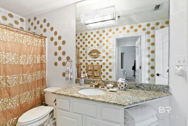 bathroom with toilet, vanity, and a textured ceiling