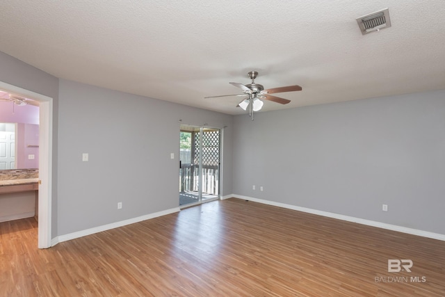 empty room with light wood-style flooring, ceiling fan, baseboards, and visible vents