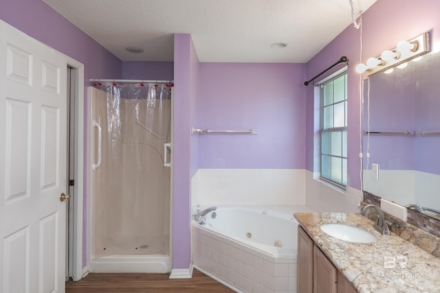 bathroom featuring a shower stall, a textured ceiling, wood finished floors, and a whirlpool tub