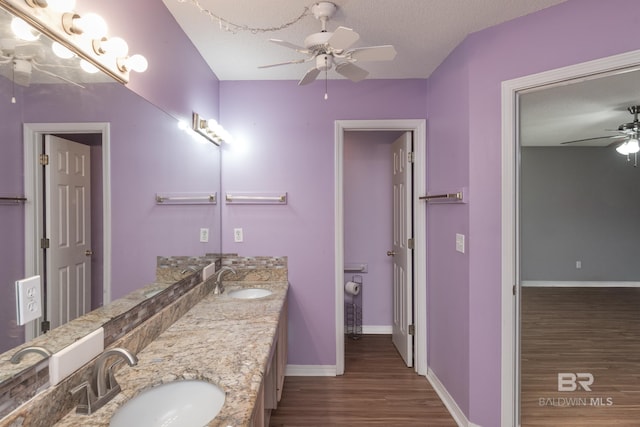 bathroom with wood finished floors, a sink, a ceiling fan, and baseboards