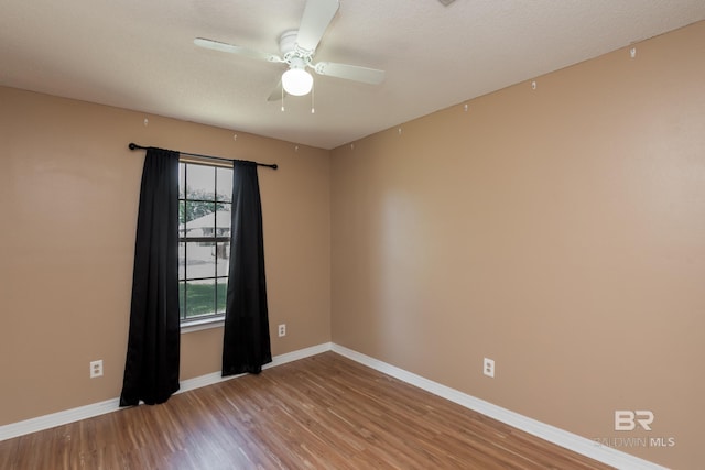spare room with wood finished floors, baseboards, and a ceiling fan