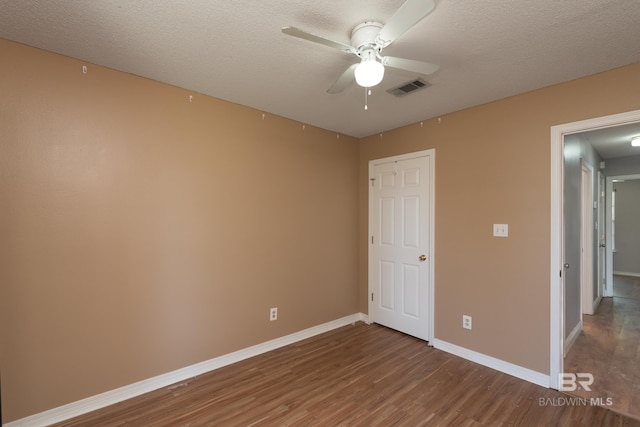 unfurnished bedroom featuring visible vents, baseboards, ceiling fan, a textured ceiling, and wood finished floors