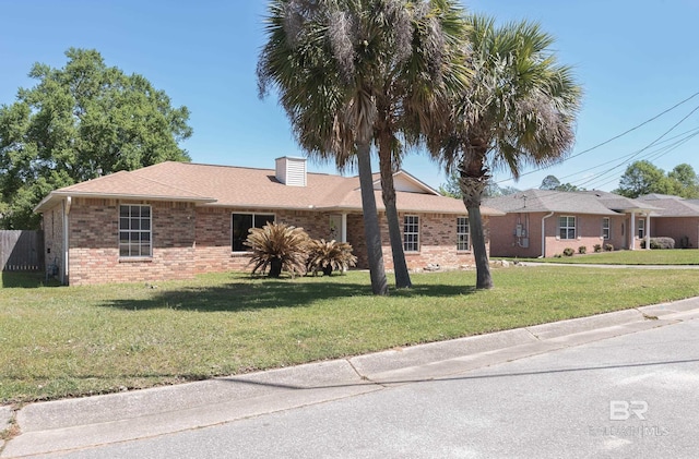 single story home featuring brick siding, a front lawn, and a chimney