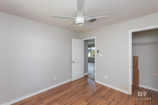 unfurnished bedroom featuring visible vents, baseboards, a closet, and wood finished floors
