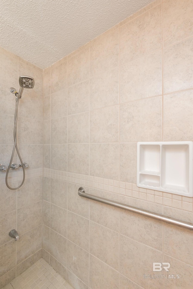 full bath with a tile shower and a textured ceiling