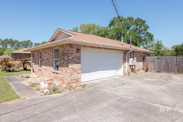 view of home's exterior with concrete driveway, brick siding, fence, and a garage
