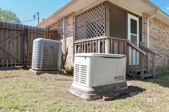 details featuring brick siding, fence, cooling unit, and a power unit