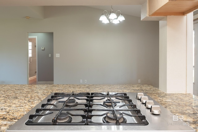 kitchen featuring hanging light fixtures, stainless steel gas stovetop, a notable chandelier, and light stone counters