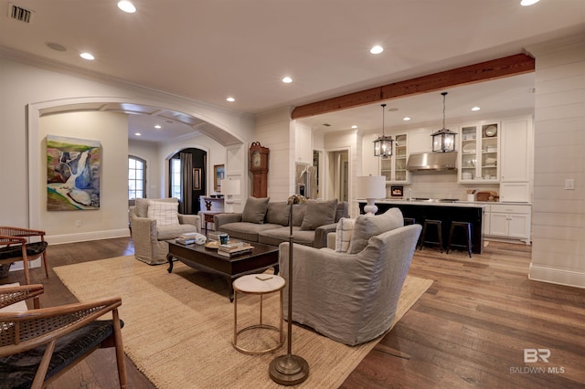 living room with visible vents, ornamental molding, recessed lighting, wood finished floors, and arched walkways